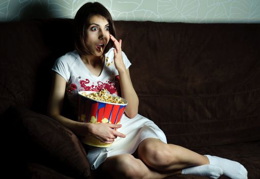 An image of woman watching TV with popcorn