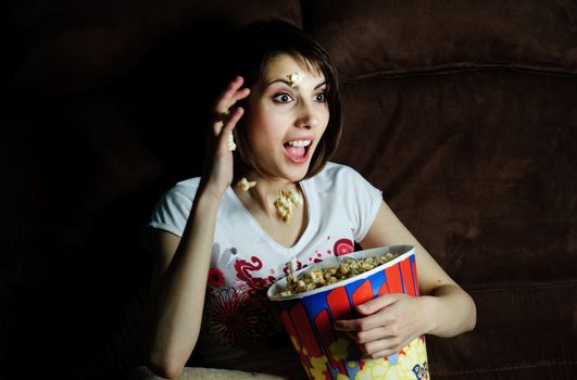 An image of woman watching TV with popcorn