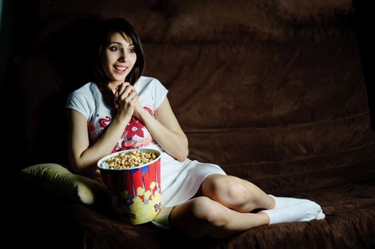 An image of a girl on a sofa watching television