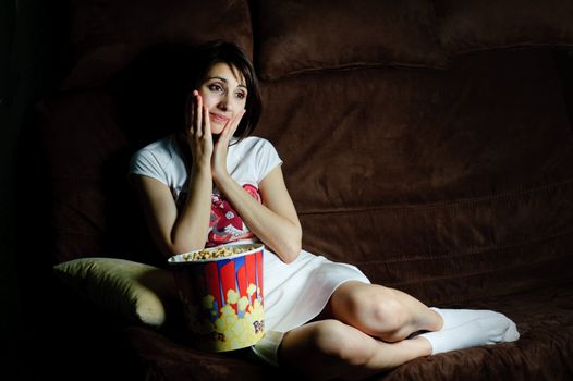 An image of a girl on a sofa watching TV