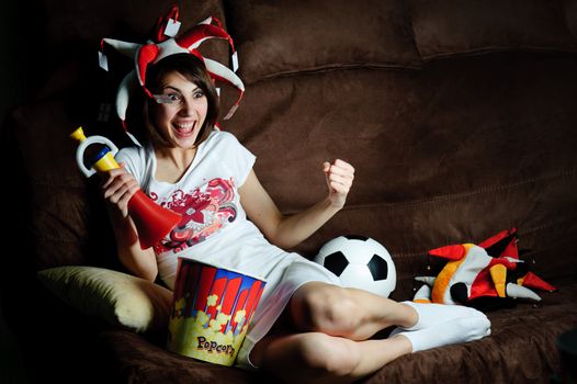 An image of a girl on a sofa watching football on TV