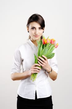 An image of young woman holding a bunch of orange tulips