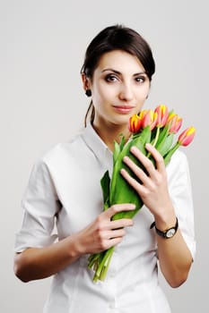 An image of young woman holding a bunch of orange tulips