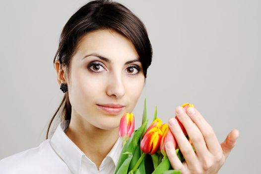 An image of young woman holding a bunch of orange tulips