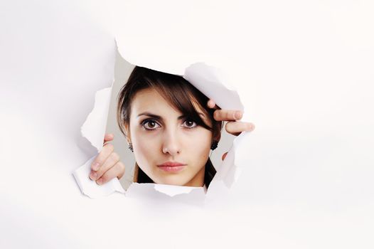 Young woman looking through hole in white paper