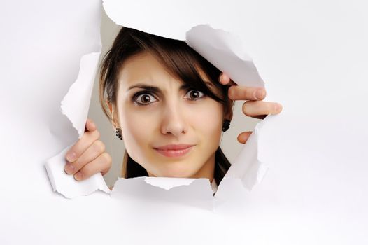 Young girl looking through hole in white paper