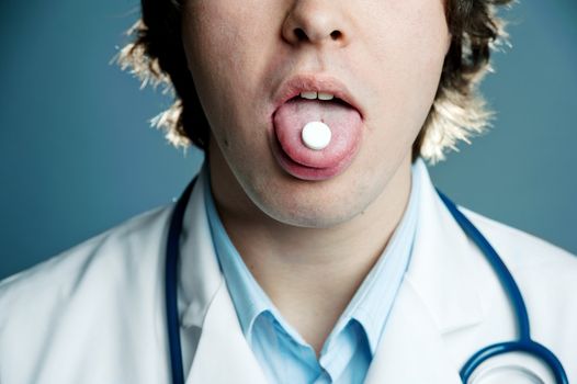 An image of a tablet in the mouth of a doctor