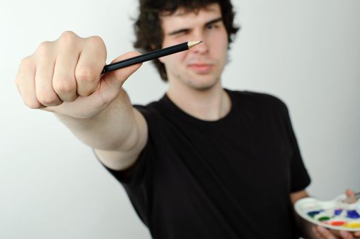 Man making eye-measure with pencil.