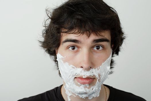 An image of a young man with shaving foam on his face