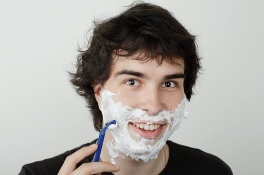 An image of a young handsome man shaving