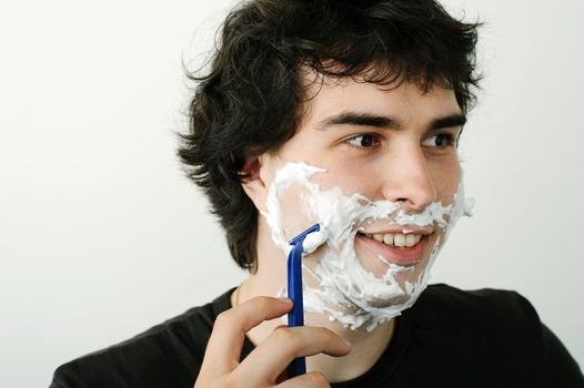 An image of a young handsome man shaving