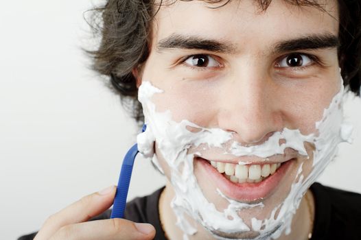 An image of a young handsome man shaving