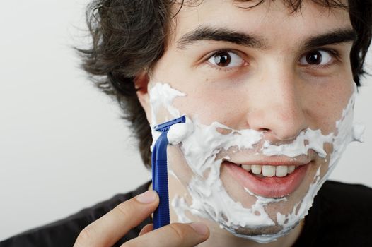 An image of a young handsome man shaving