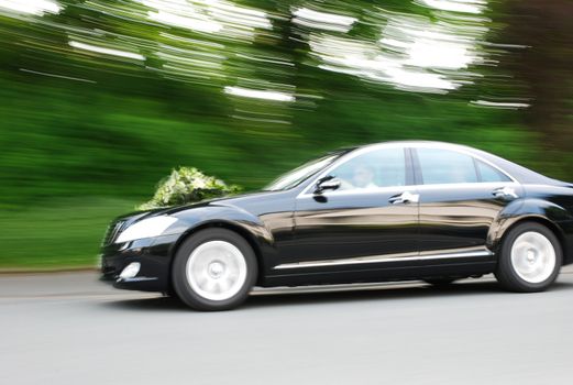 Elegant bridal car speeding with flowers on hood. Motionblur