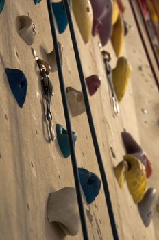 homemade artificial climbing wall covered with colored holds and ropes for rock climbing training