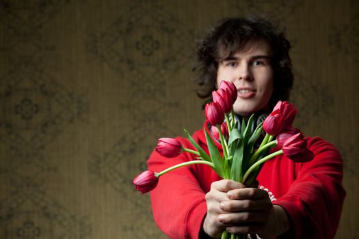 A portrait of a young man with red tulips