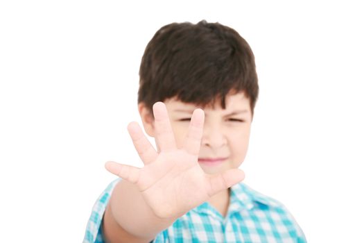 Child looking at camera. Stop signal with his hand. Boy trying to defend himself isolated on white
