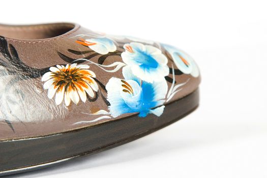 detail from brown women high heels shoes with printed flower on white background