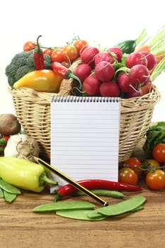 Ruled shopping list with fresh vegetables on a wooden ground