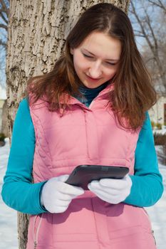 Teen girl with e-book reader in a park at winter time