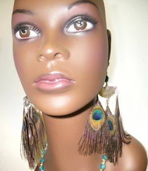Mannequin head wearing handmade peacock feather earrings.