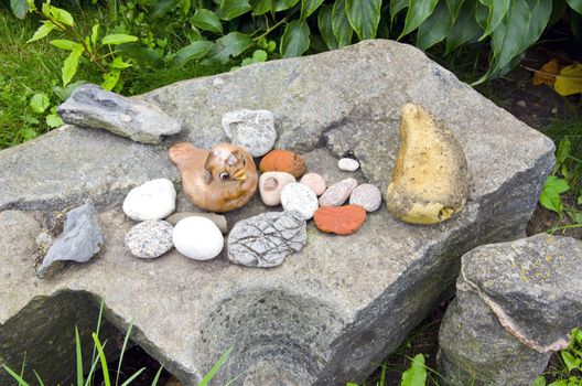 Ancient vintage retro rock stone in garden and decorative objects figure of bird.