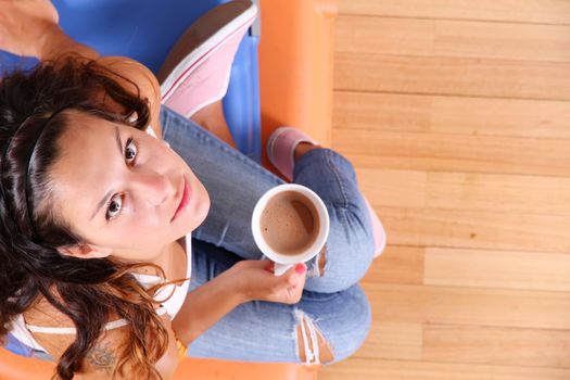 A young woman sitting on a stack of suitcases while drinking coffee and waiting for the departure to vacations.