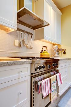 Close up of the white kitchen with stainless steal stove and hood.