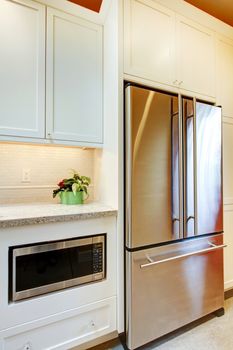 Stainless steal refridgirator with microwave and white cabinets.