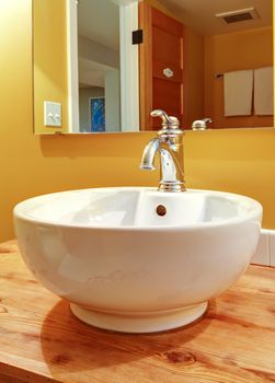 Round white sink with faucet and natural pine wood.