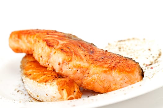 Fried salmon fillets with sauce on white plate