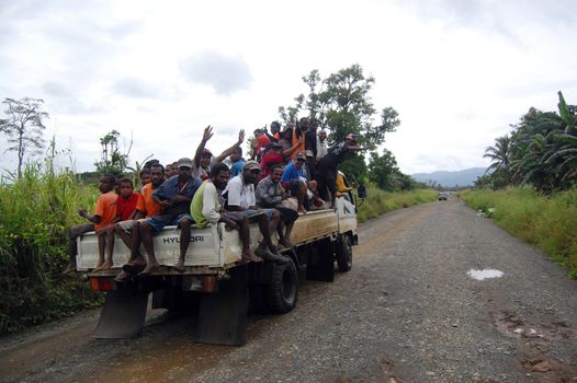 People are sitting on PMV which is driving on the road, Papua New Guinea