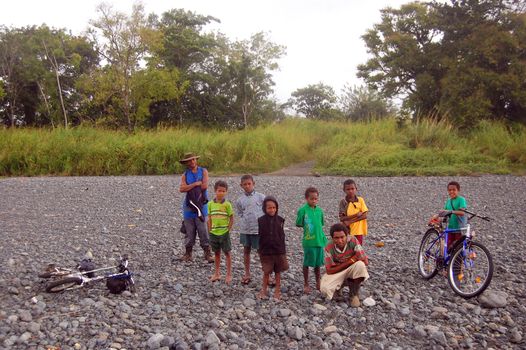 Papuan kids with bycicle at the riverside, Maregiuina village, Papua New Guinea