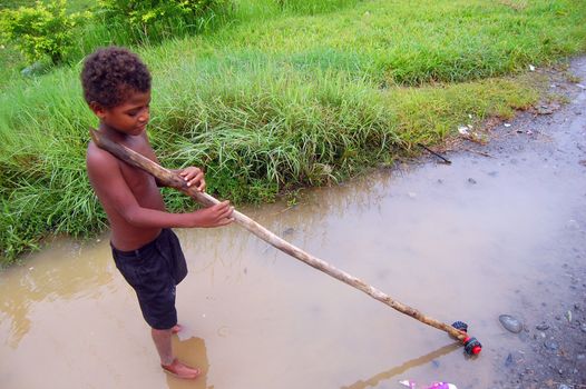 Papuan boy with toy in the village road, Papua New Guinea