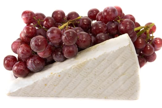 Picture of some grapes in the background, and a slice of brie on the foreground
