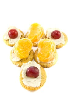 Picture of some crackers with cheese with some grapes and clementins on top