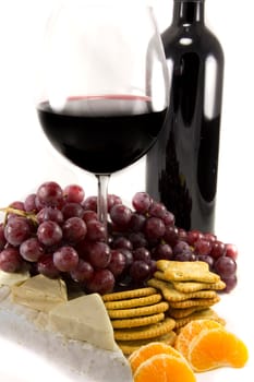 Picture of a bottle of red wine with grapes around, and crackers and clementins