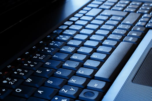 close up of laptop keyboard as a background toned to blue