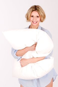 blonde hair, standing with pillow cushions. She is wearing a nightgown and smiles