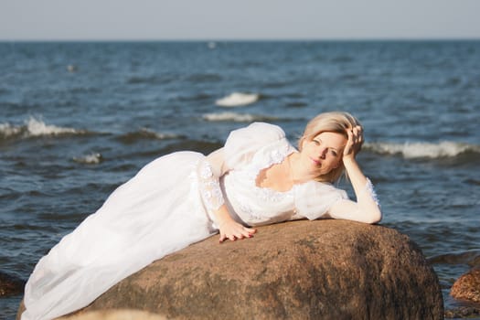 Beautiful  woman lying on the big stone at the seaside