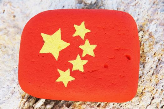 painted stone with the colouors of the chinese flag on the rock at the beach