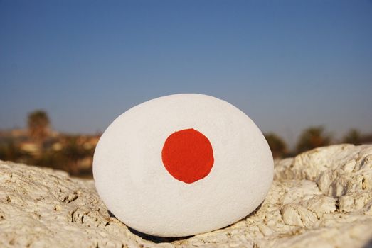 closeup shot over a stone with the colours of the japan flag over a rock