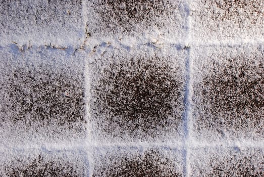 Snow falls on the snow-covered tile in winter.