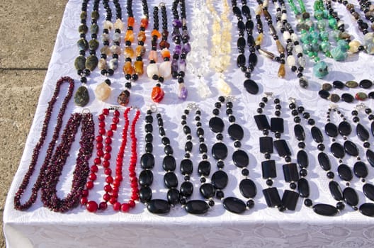 Earrings on table for sale in outside street fair market. Decorative jewelry from precious stones.