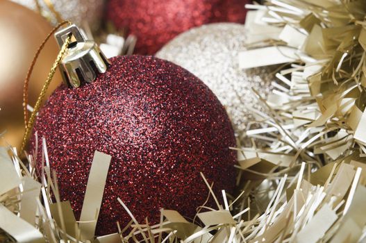 Close up shot of a variety of Christmas baubles and gold tinsel.  Red bauble in foreground.  Shallow depth of field.  