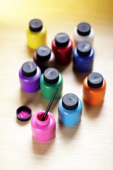 Group of paints bottles of various colors on a table, view from above
