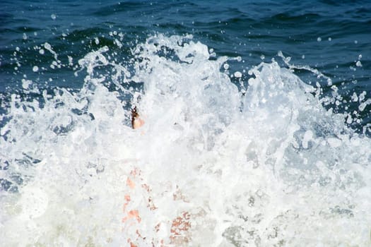 young boy in ocean overcome by huge wave and splash