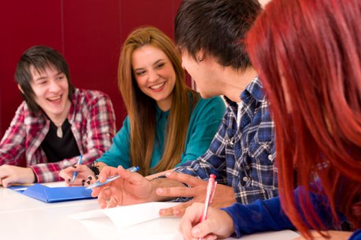 Happy smiling classmates sitting at a desk