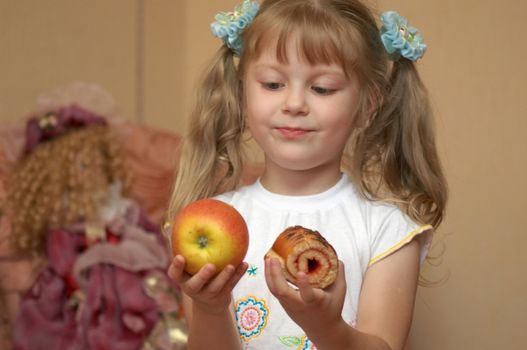 A girl holding an apple and a cake