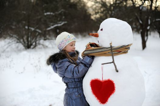 An image of little girl near big snowman